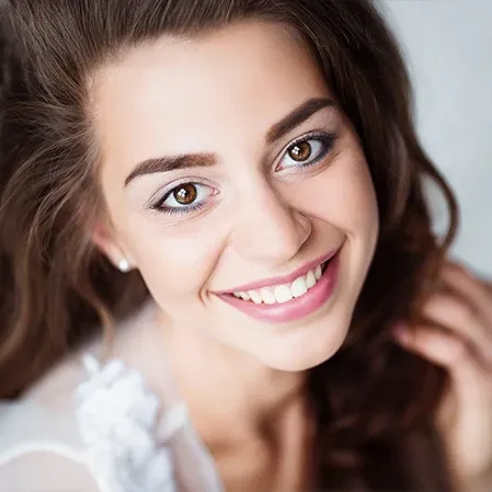 Close-up portrait of a person with long hair looking toward the camera against a light background.